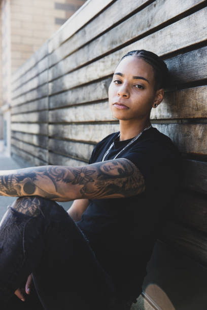 African American woman with braided hair wearing a black t-shirt sits outside
